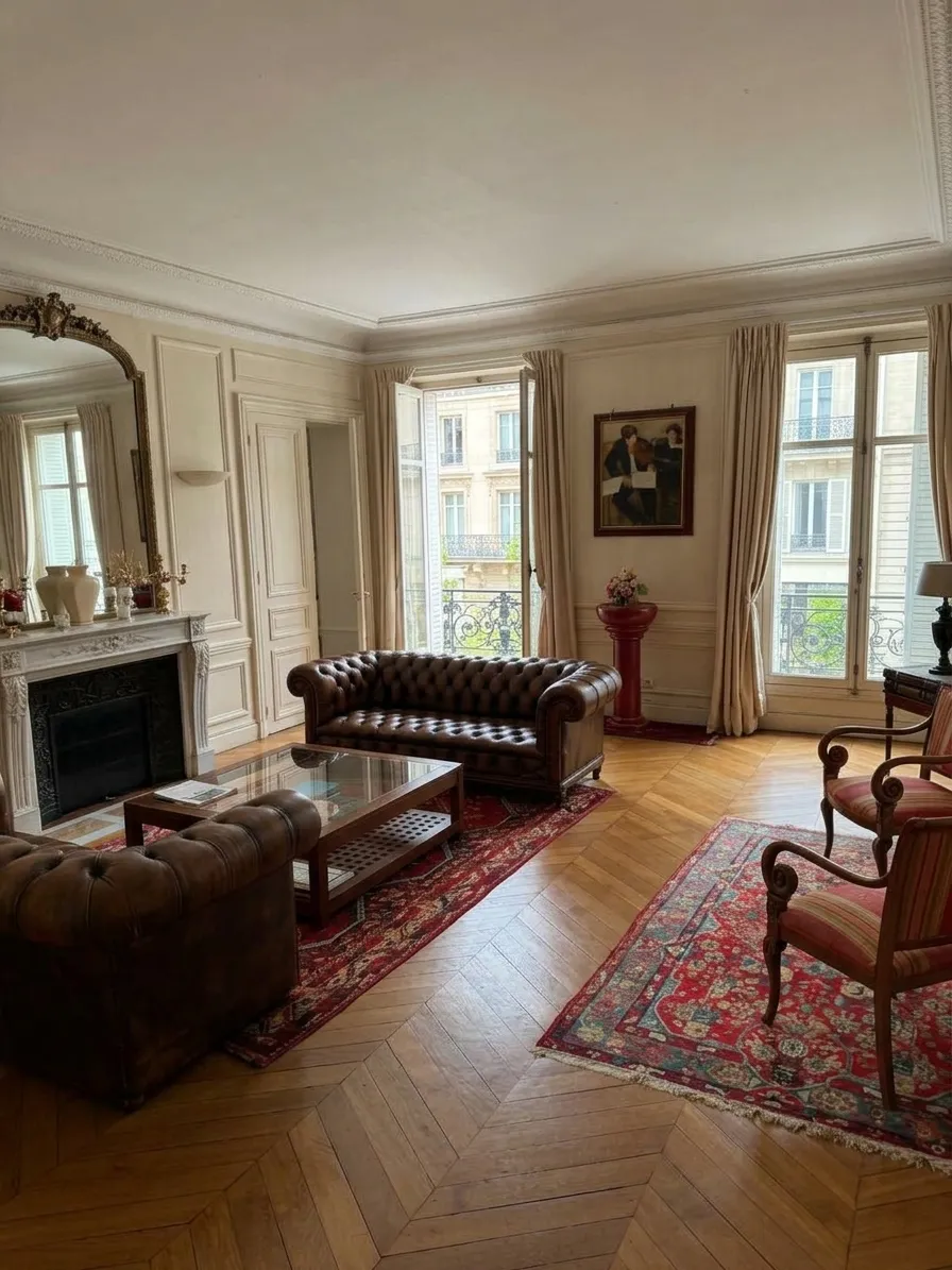 Salle d'attente du cabinet dans un appartement haussmannien : canapés Chesterfield, cheminée en marbre et parquet en point de Hongrie